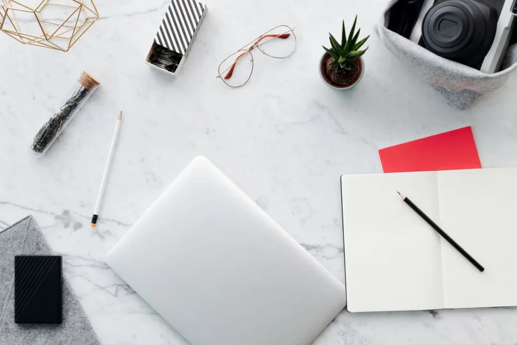 Flat lay of a tidy home office desk with a laptop, notebook, plant and desk accessories