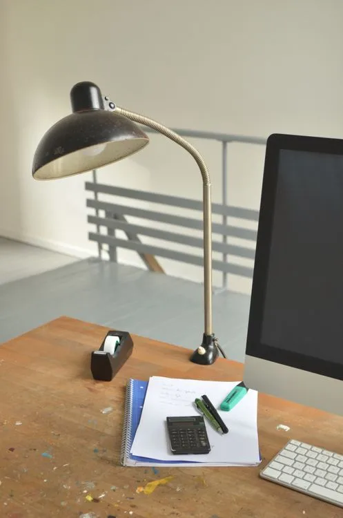 Desk lamp lighting a home office desk with notebook, keyboard and monitor