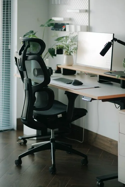 Ergonomic home office with mesh chair, standing desk, monitor and desk lamp