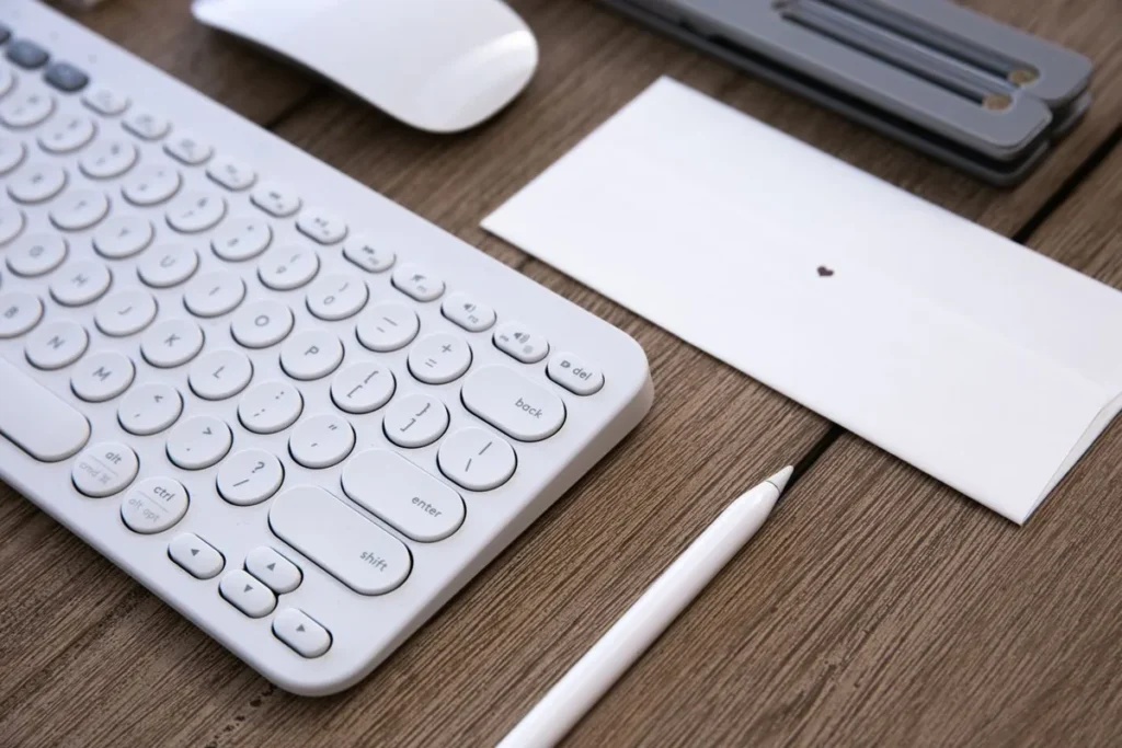White low-profile wireless keyboard and mouse on a wooden desk