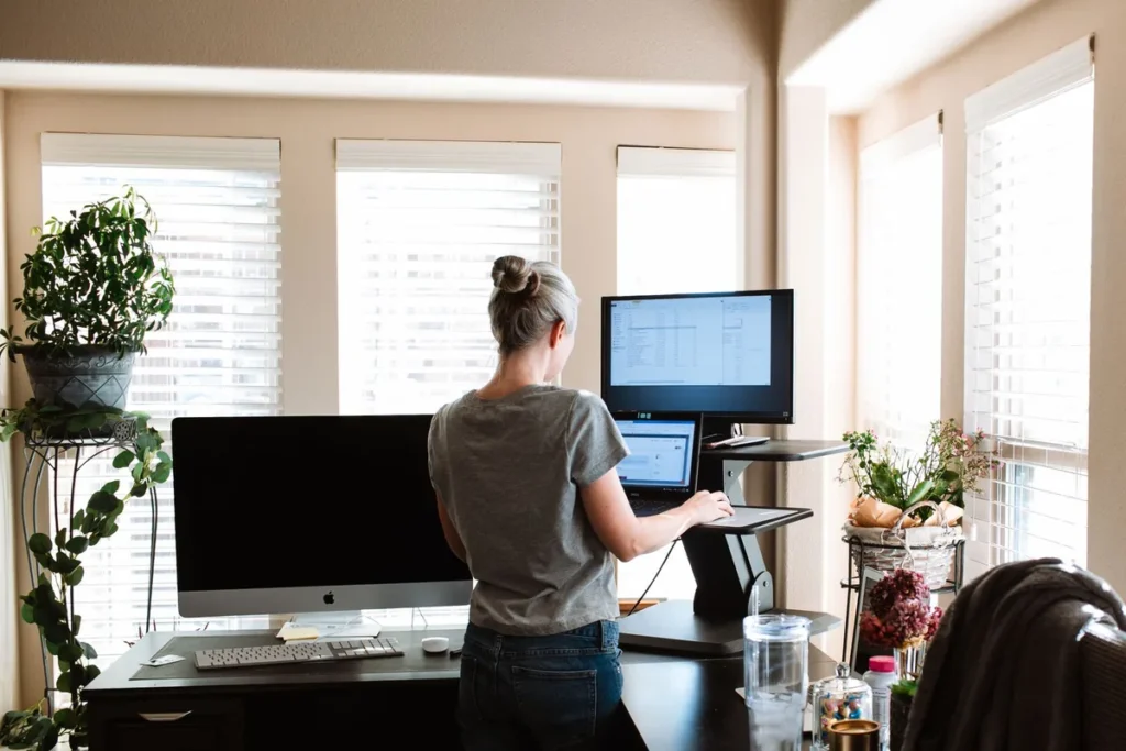 Woman working at a standing desk raised to standing height in a bright home office